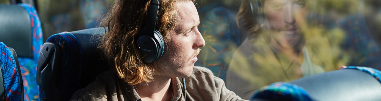 passenger wearing headphones looking out coach window